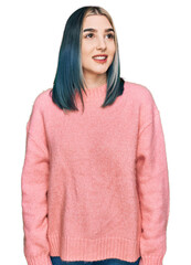 Wall Mural - Young modern girl wearing pink wool winter sweater looking away to side with smile on face, natural expression. laughing confident.