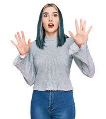 Wall Mural - Young modern girl wearing casual sweater afraid and terrified with fear expression stop gesture with hands, shouting in shock. panic concept.