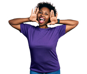 Poster - African american woman with afro hair wearing casual purple t shirt smiling cheerful playing peek a boo with hands showing face. surprised and exited