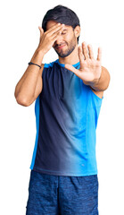 Canvas Print - Handsome hispanic man wearing sportswear covering eyes with hands and doing stop gesture with sad and fear expression. embarrassed and negative concept.