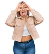 © Krakenimages.com - Hispanic woman with pink hair wearing casual clothes doing ok gesture like binoculars sticking tongue out, eyes looking through fingers. crazy expression.