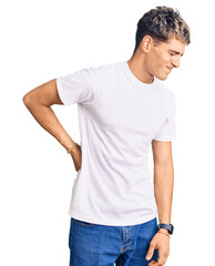 Young handsome man wearing casual white tshirt suffering of backache, touching back with hand, muscular pain