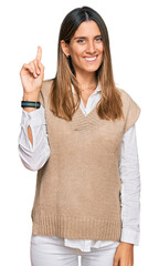 Wall Mural - Young woman wearing casual clothes showing and pointing up with finger number one while smiling confident and happy.