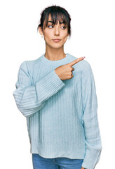 Young hispanic woman wearing casual clothes pointing with hand finger to the side showing advertisement, serious and calm face