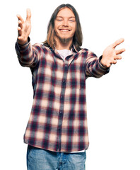 Sticker - Handsome caucasian man with long hair wearing hipster shirt looking at the camera smiling with open arms for hug. cheerful expression embracing happiness.