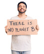 © Krakenimages.com - Young hispanic man holding there is no planet b banner looking positive and happy standing and smiling with a confident smile showing teeth