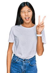 Poster - Beautiful young asian woman wearing casual white t shirt smiling with happy face winking at the camera doing victory sign with fingers. number two.