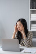 © kamiphotos - Beautiful asian woman suffering from stress due to working long hours and job problems, young business woman having office syndrome from overwork causing pain, headache. Office syndrome concept.