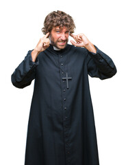 Canvas Print - Handsome hispanic catholic priest man over isolated background covering ears with fingers with annoyed expression for the noise of loud music. Deaf concept.