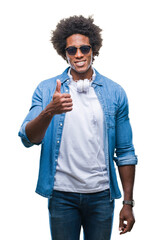 Sticker - Afro american man wearing headphones listening to music over isolated background doing happy thumbs up gesture with hand. Approving expression looking at the camera with showing success.