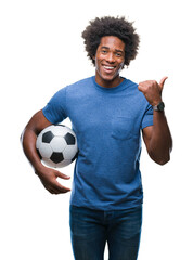 Wall Mural - afro american man holding football ball over isolated background pointing and showing with thumb up 