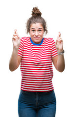 Poster - Beautiful brunette curly hair young girl wearing casual look over isolated background smiling crossing fingers with hope and eyes closed. Luck and superstitious concept.