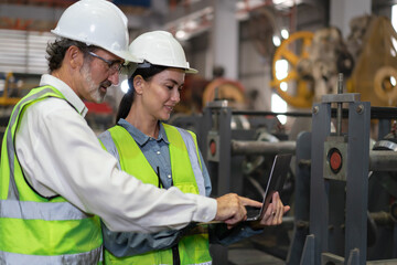 Wall Mural - Industrial engineer and colleague wear safety helmets examining production in heavy metal engineering factories. Beard man industry inspector inspecting metalwork in manufacturing warehouse facility.