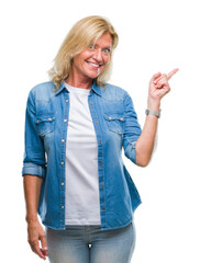 Poster - Middle age blonde woman over isolated background with a big smile on face, pointing with hand and finger to the side looking at the camera.