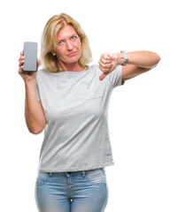 Poster - Middle age blonde woman showing blank screen of smartphone over isolated background with angry face, negative sign showing dislike with thumbs down, rejection concept