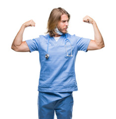 Sticker - Young handsome doctor man with long hair over isolated background showing arms muscles smiling proud. Fitness concept.