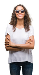 Poster - Young hispanic woman wearing sunglasses happy face smiling with crossed arms looking at the camera. Positive person.