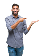 Canvas Print - Adult hispanic man over isolated background amazed and smiling to the camera while presenting with hand and pointing with finger.