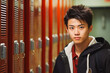 Chinese teenage boy portrait in front of school lockers. Learning and school concept. Generative AI