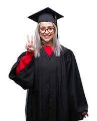 Wall Mural - Young blonde woman wearing graduate uniform over isolated background showing and pointing up with fingers number two while smiling confident and happy.