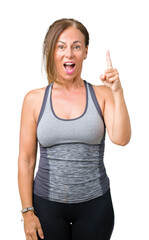 Poster - Beautiful middle age woman wearing sport clothes over isolated background pointing finger up with successful idea. Exited and happy. Number one.