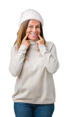 Poster - Beautiful middle age woman wearing winter sweater and hat over isolated background Smiling with open mouth, fingers pointing and forcing cheerful smile