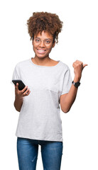 Young african american woman using smartphone over isolated background pointing and showing with thumb up to the side with happy face smiling
