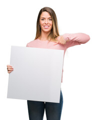 Canvas Print - Beautiful young woman holding advertising banner with surprise face pointing finger to himself