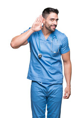 Poster - Handsome young doctor surgeon man over isolated background smiling with hand over ear listening an hearing to rumor or gossip. Deafness concept.