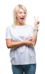 Wall Mural - Young beautiful blonde woman wearing white t-shirt over isolated background smiling with happy face winking at the camera doing victory sign. Number two.