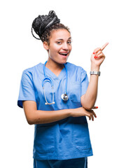 Sticker - Young braided hair african american girl professional surgeon over isolated background with a big smile on face, pointing with hand and finger to the side looking at the camera.