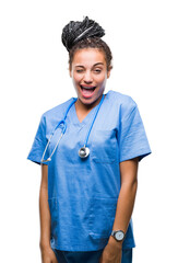 Sticker - Young braided hair african american girl professional surgeon over isolated background winking looking at the camera with sexy expression, cheerful and happy face.