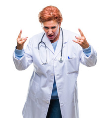 Canvas Print - Senior caucasian doctor woman wearing medical uniform over isolated background shouting with crazy expression doing rock symbol with hands up. Music star. Heavy concept.