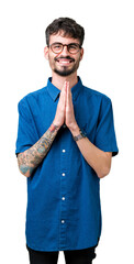 Wall Mural - Young handsome man wearing glasses over isolated background praying with hands together asking for forgiveness smiling confident.