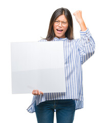 Canvas Print - Young asian woman over isolated background holding blank banner annoyed and frustrated shouting with anger, crazy and yelling with raised hand, anger concept