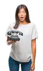 Sticker - Young asian woman holding vintagera telephone over isolated background scared in shock with a surprise face, afraid and excited with fear expression