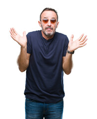 Wall Mural - Middle age hoary senior man wearing sunglasses over isolated background clueless and confused expression with arms and hands raised. Doubt concept.