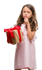 Wall Mural - Brunette hispanic girl holding a gift serious face thinking about question, very confused idea