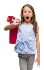 Poster - Brunette hispanic girl holding shopping bags scared in shock with a surprise face, afraid and excited with fear expression