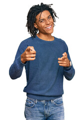 Wall Mural - Young african american man wearing casual winter sweater pointing fingers to camera with happy and funny face. good energy and vibes.