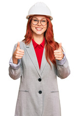 Poster - Young redhead woman wearing architect hardhat success sign doing positive gesture with hand, thumbs up smiling and happy. cheerful expression and winner gesture.