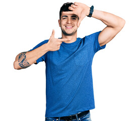 Young hispanic man wearing casual t shirt smiling making frame with hands and fingers with happy face. creativity and photography concept.