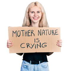 Poster - Young caucasian woman holding mother nature is crying protest cardboard banner smiling with a happy and cool smile on face. showing teeth.