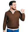 © Krakenimages.com - Young hispanic man wearing casual clothes pointing thumb up to the side smiling happy with open mouth