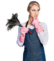 Sticker - Beautiful young blonde woman wearing apron holding cleaning duster thinking worried about a question, concerned and nervous with hand on chin