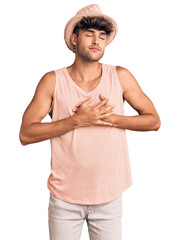 Sticker - Young hispanic man wearing summer hat smiling with hands on chest with closed eyes and grateful gesture on face. health concept.