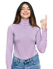 Sticker - Young beautiful teen girl wearing turtleneck sweater showing and pointing up with finger number one while smiling confident and happy.