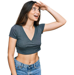 Poster - Young beautiful teen girl wearing casual crop top t shirt very happy and smiling looking far away with hand over head. searching concept.