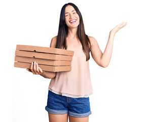 Sticker - Young beautiful caucasian woman holding delivery pizza box celebrating victory with happy smile and winner expression with raised hands