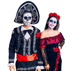 Sticker - Young couple wearing mexican day of the dead costume over background winking looking at the camera with sexy expression, cheerful and happy face.